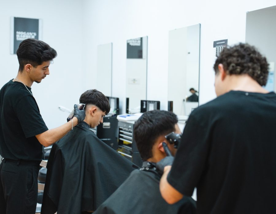 Experiencia de barbería premium en Mogan’s con estilistas profesionales realizando cortes personalizados en un ambiente moderno.